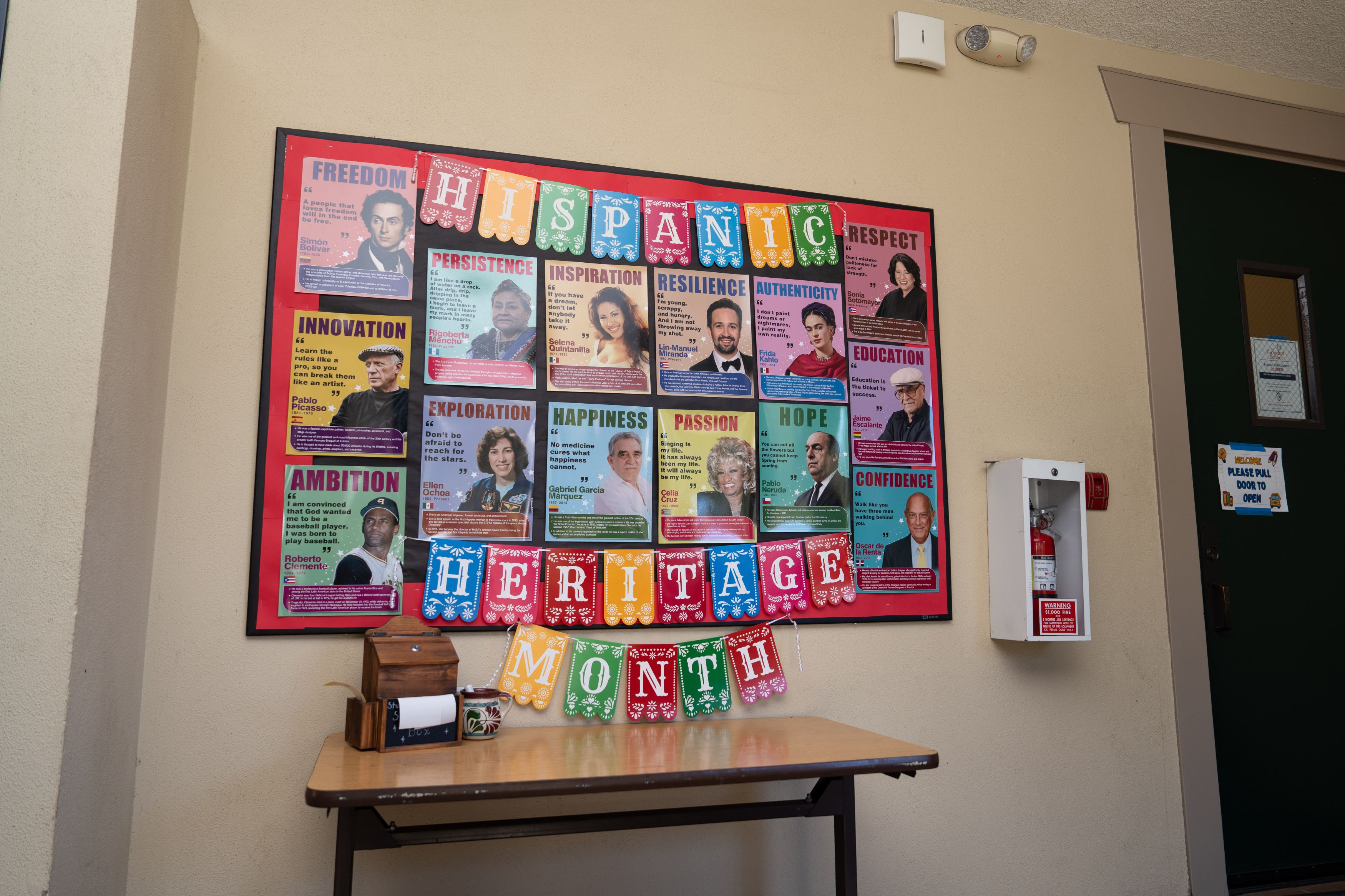 A bulletin board displays posters of notable figures for Hispanic Heritage Month, featuring quotes on themes like freedom, innovation, and resilience.