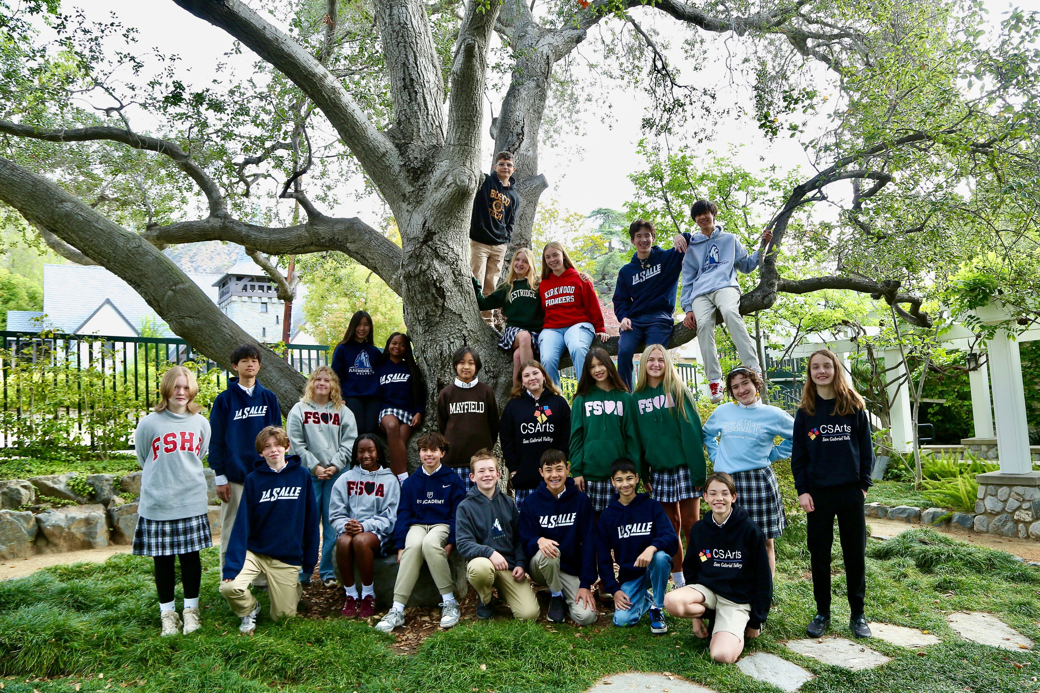 Class of 2026 students pose under a large tree wearing school sweatshirts labeled FSH, La Salle, Mayfield, CSArts, and others.